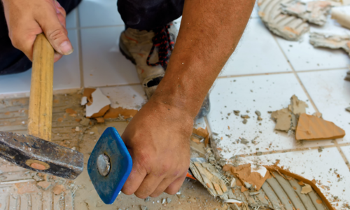 Handwerker entfernt mit Hammer und Meißel Bodenfliesen | © CRB Analyse Service GmbH